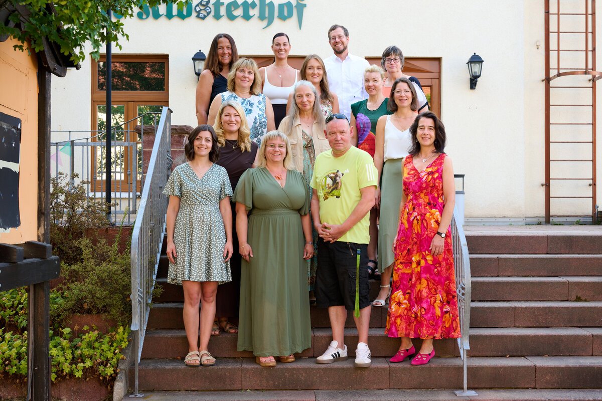 Das Kollegium der Grundschule Georgenthal vor der grünen Wand des Schulgebäudes